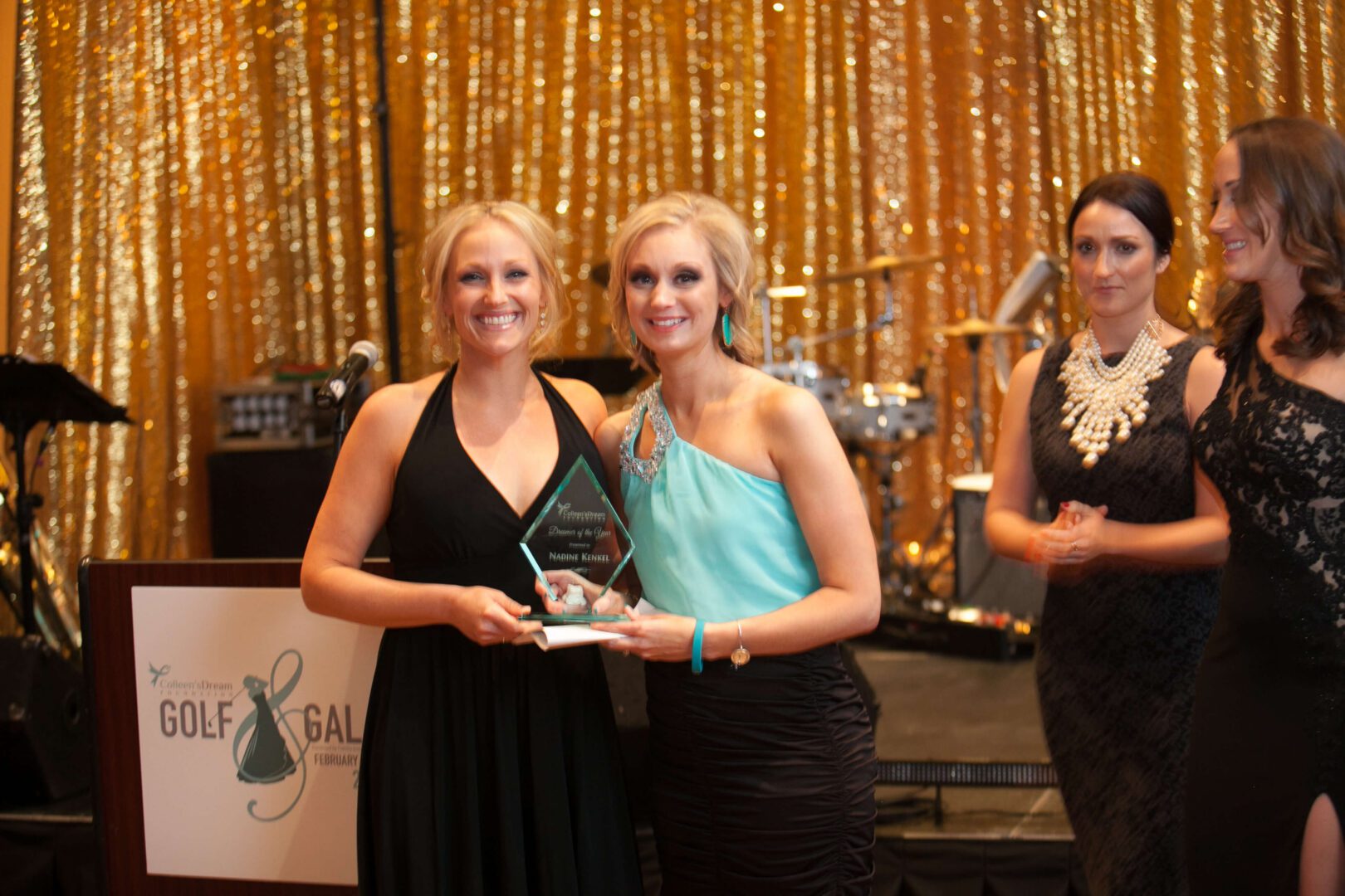 Two women holding an award on stage.
