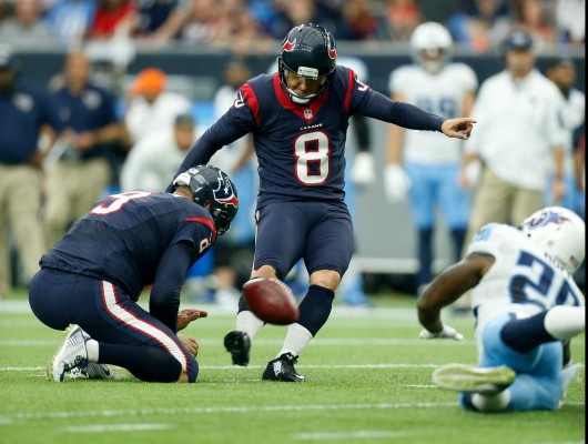 A football player, Nick Novak, is kicking the ball in a game.