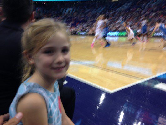 Young girl smiling at basketball game.