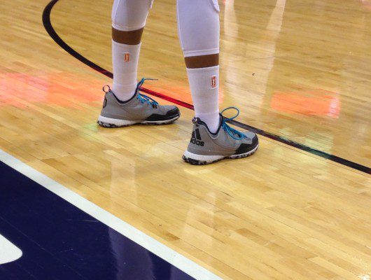 Basketball player wearing Adidas shoes on court.