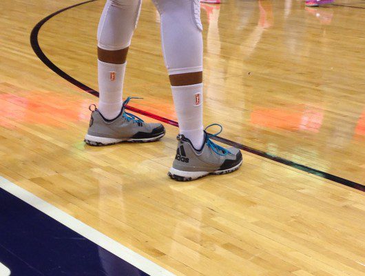 Athlete wearing sneakers on basketball court.