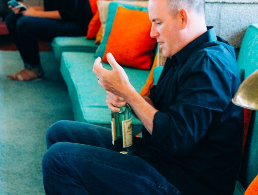 Man seated on couch holding a bottle.