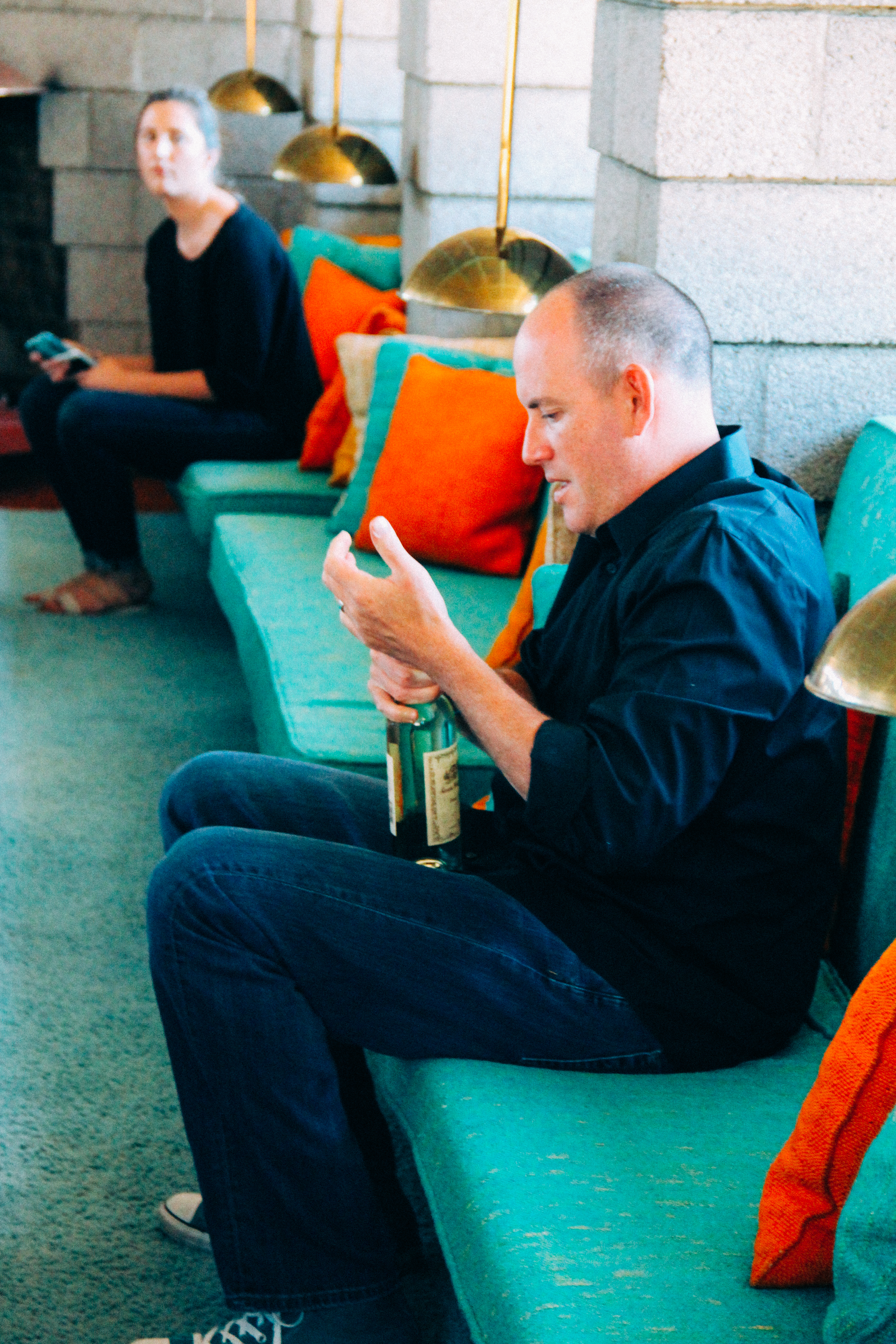 Man seated on couch holding a bottle.