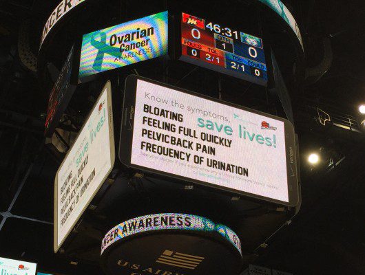 Ovarian cancer awareness signs on stadium scoreboard.