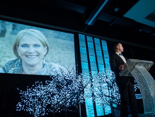 Speaker at podium with large projected portrait.