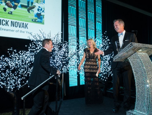 Award ceremony with three people on stage.