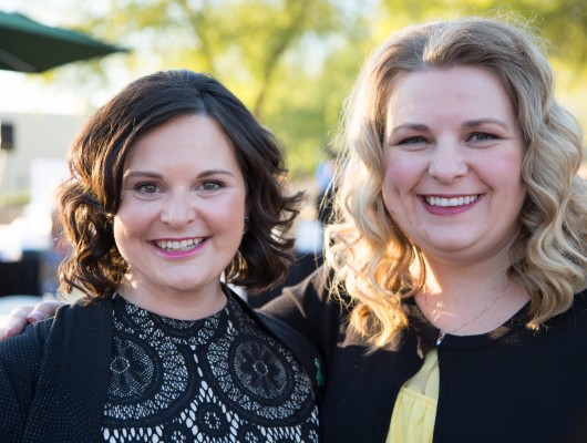 Two smiling women posing outdoors together.