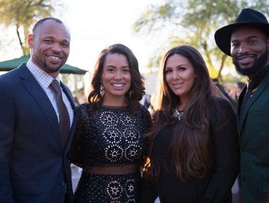 Group of four people smiling outdoors.