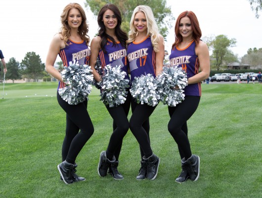 Cheerleaders posing on a grassy field.