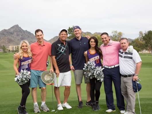 Group of people smiling on a golf course.