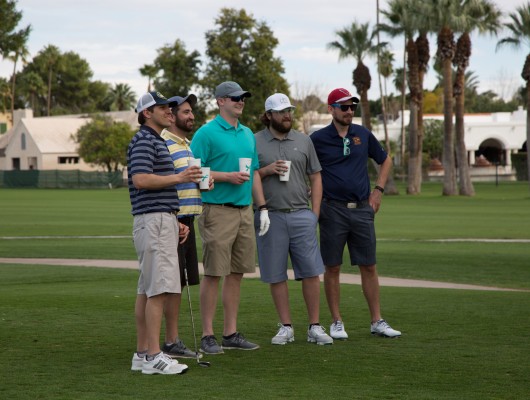Five men standing on a golf course.