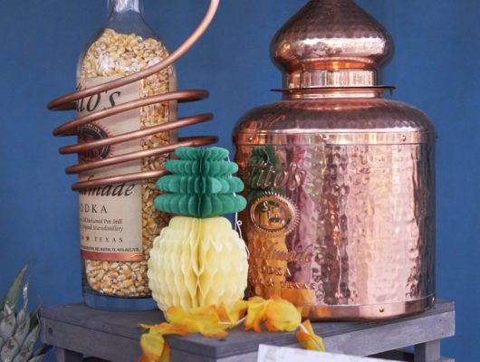 Copper still with decorative bottle and flowers.