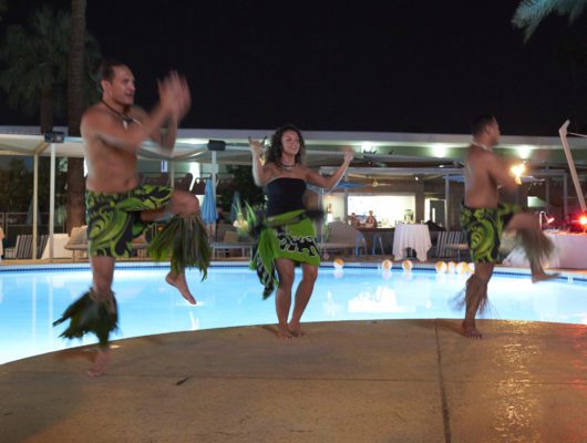 Dancers performing by a poolside at night.