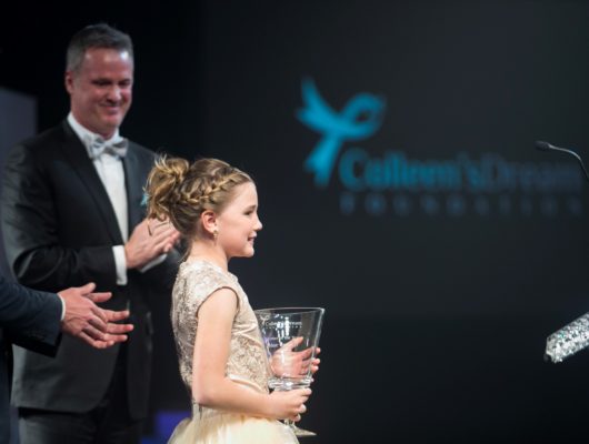 A young girl receives an award from a man at an awards ceremony.