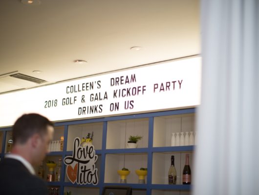 A man is standing in front of a sign that says college's dream party.